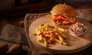 A mouthwatering cheeseburger with fresh fries and coleslaw on a rustic wooden board.