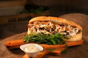 Delicious chicken sandwich with mayonnaise and greens served on a wooden board.